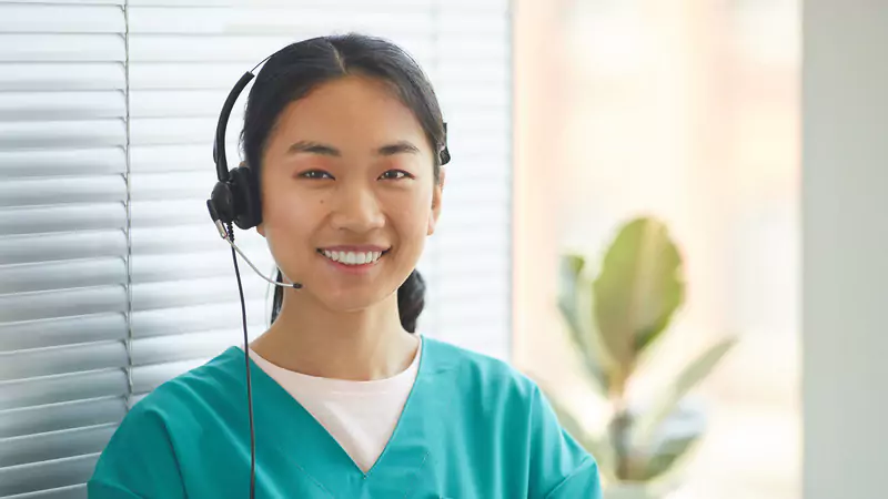 Smiling informatics nurse wearing headset, illustrating best practices in overcoming healthcare technology implementation challenges