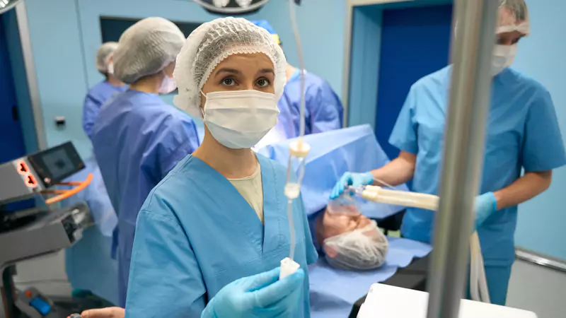 Nurse anesthetist monitoring IV medication during surgery, showcasing precision in anesthesia management