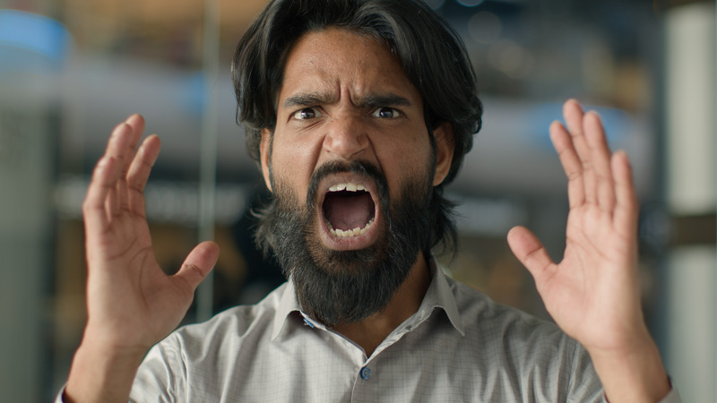 Close-up of an angry, emotional man yelling with hands raised