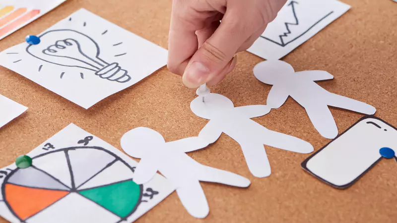 Hand pinning paper figures and notes to corkboard illustrating strategies to maximize travel nurse earnings