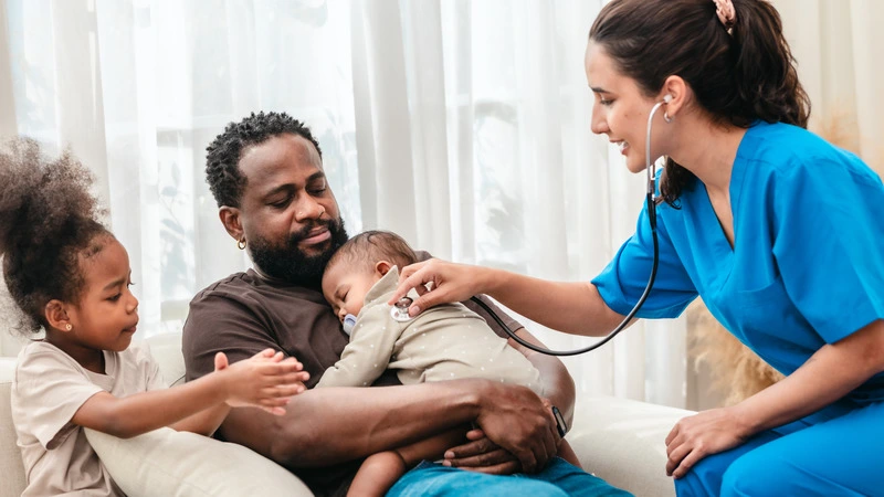 Nurse in blue scrubs examining a baby held by father, representing highest paying nursing jobs in pediatric care