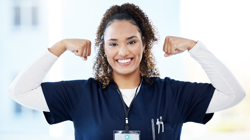 Smiling healthcare worker flexing arm muscles in hospital setting