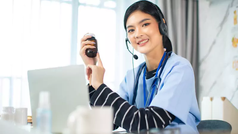 Remote nurse holding medication bottle during virtual consultation, symbolizing the launch of an online nursing career