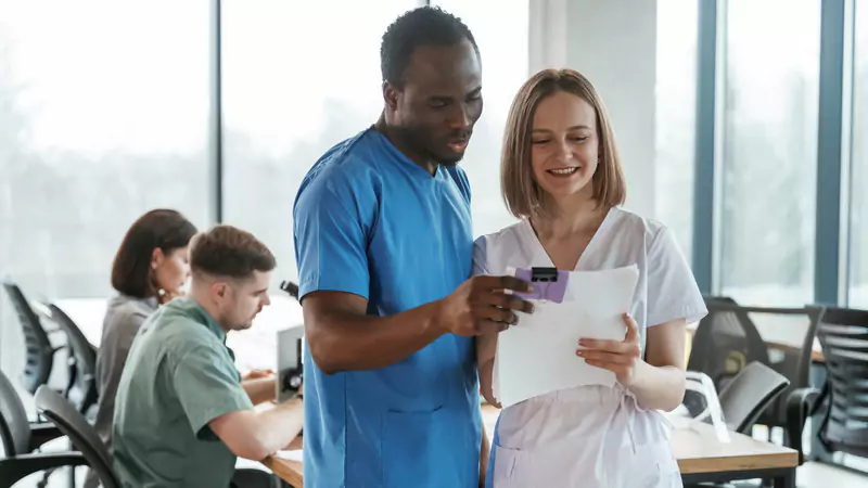 Two nurses reviewing documents related to factors affecting travel nurse salary and pay rates