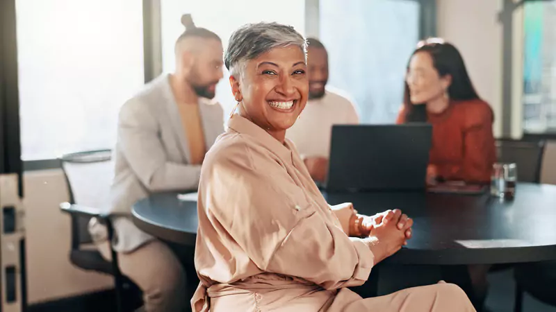 smiling-retired-nurse-sitting-in-office-meeting-showing-successful-retirement