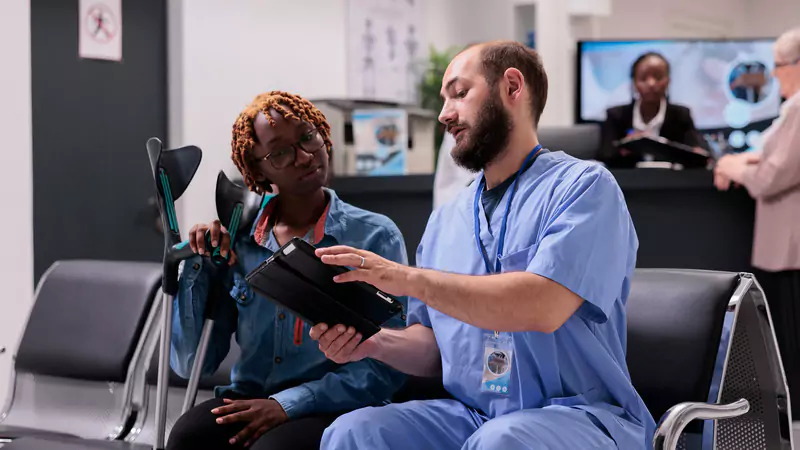 Informatics nurse discussing healthcare data with patient using digital tablet, emphasizing effective data management