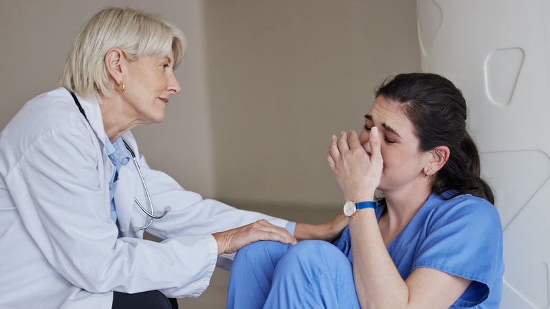 Senior doctor comforting distressed nurse in hospital setting