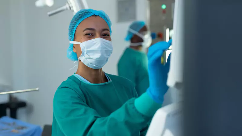 Smiling nurse anesthetist confidently operating medical equipment, symbolizing excellence in CRNA career