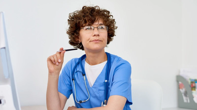 Thoughtful nurse at desk planning career moves toward highest paying nursing jobs