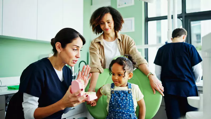 pediatric-nurse-teaching-child-tooth-care-in-clinic