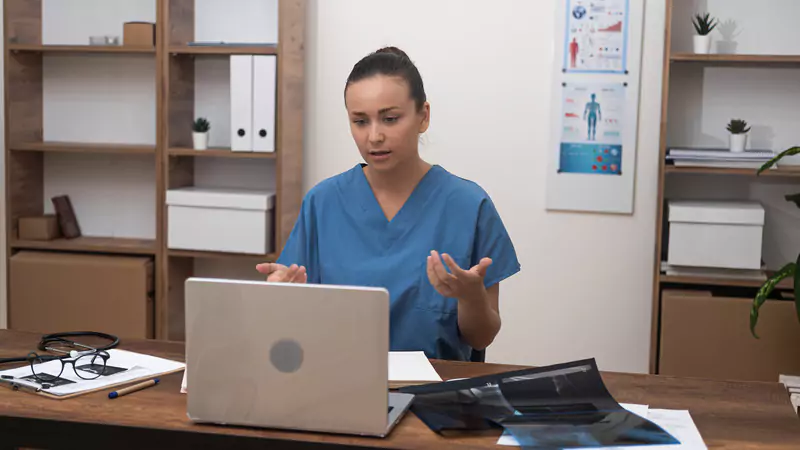 nurse-in-scrubs-reviewing-medical-records-on-video-call