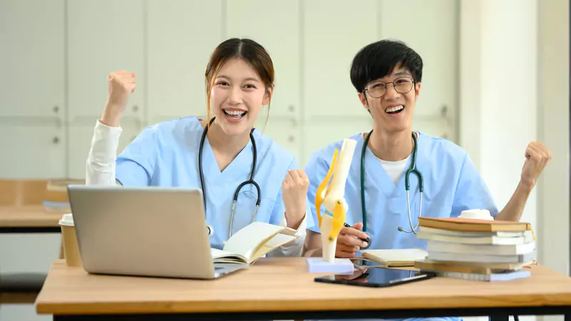 smiling-nursing-students-celebrating-while-studying-at-desk
