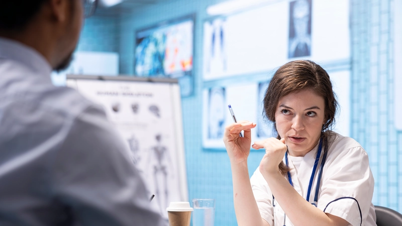 Nurse having a serious discussion with a colleague in a clinical setting, illustrating real-life political challenges in hospital environments