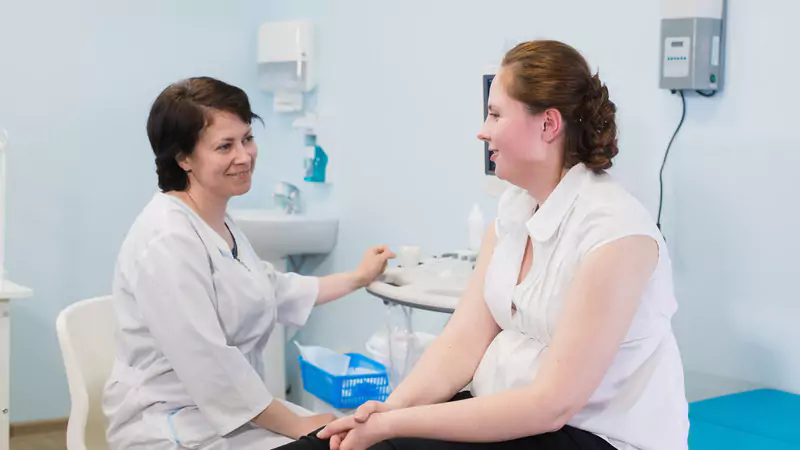 nurse-midwife-talking-to-expecting-patient-in-clinic