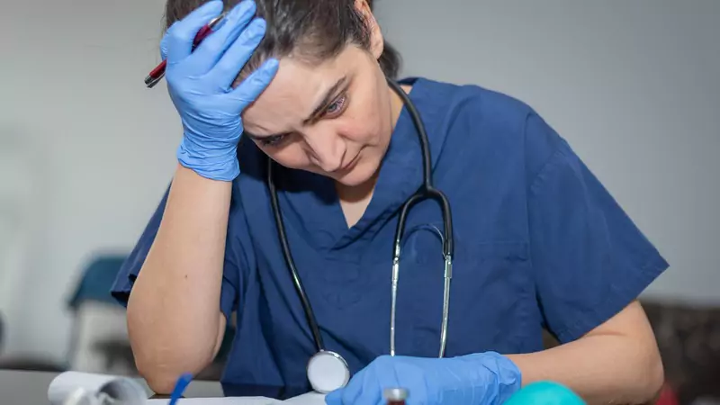 nurse-in-scrubs-feeling-stressed-and-overwhelmed-while-documenting-patient-notes