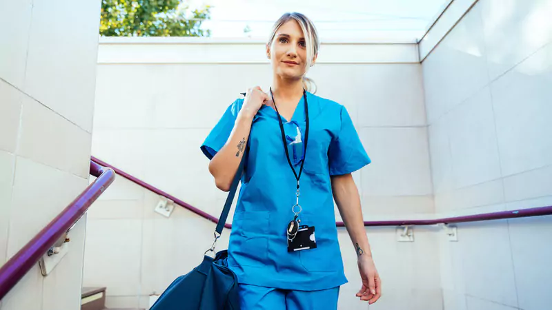 travel-nurse-in-scrubs-walking-up-subway-steps-with-bag