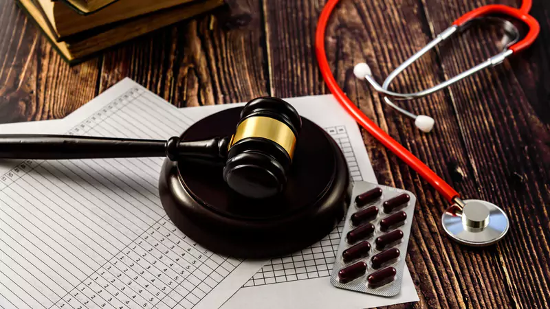 gavel-stethoscope-pills-and-medical-charts-on-wooden-desk