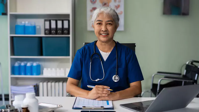 smiling-senior-nurse-consultant-at-desk-with-medical-files